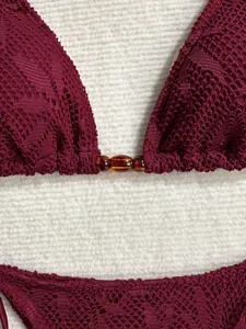 Détail d'un bikini en crochet bordeaux avec connecteur en perles ambrées.