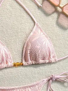 Gros plan d'un haut de bikini en dentelle rose avec détails de perles ambre