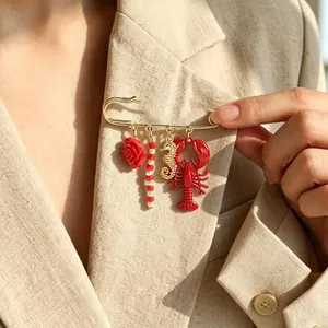 Detailed view of ocean-themed safety pin brooch with lobster and seahorse charms.