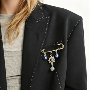 Close-up detail view of decorative evil eye and ship wheel brooch on a black blazer lapel