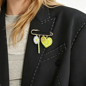 Close-up of safety pin brooch with daisy and lemon heart charms on a black blazer