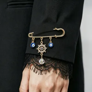Detailed shot of an ocean series safety pin brooch with evil eye and rudder charms.