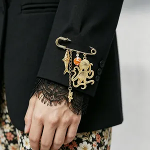 Detailed view of a gold ocean-themed brooch with octopus and fish charms on a sleeve