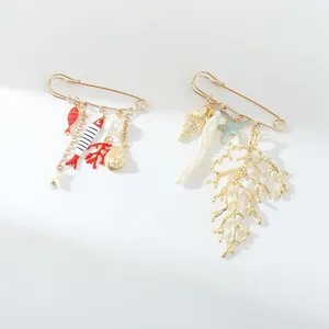 Detailed view of two ocean-themed safety pin brooches with colorful sea charms