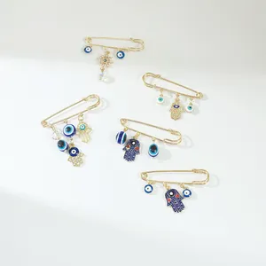 Set of gold safety pin brooches featuring evil eye and hamsa hand charms for decoration