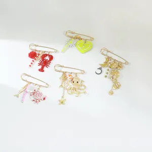 Detailed macro view of multi-style gold safety pin brooches with marine charms