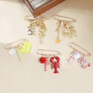 Detail of five ocean-themed gold safety pin brooches with lobster and octopus charms