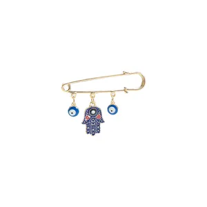 Detailed view of gold Hamsa hand and evil eye safety pin brooch accessory