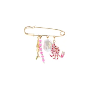 Detailed macro shot of a gold marine-themed brooch pin featuring fish and crab charms