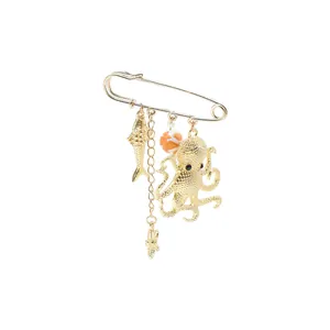 Detail view of a gold-tone ocean-themed safety pin brooch with octopus and fish charms.
