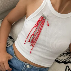 Vue détaillée d'une broche tendance à pompons de perles rouges sur un débardeur blanc