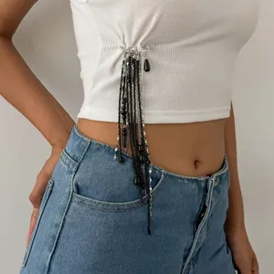 Vue détaillée d'une broche épingle avec perles noires et chaînes sur un haut blanc.