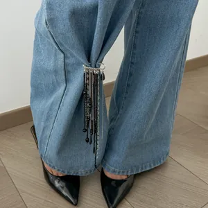 Gros plan d'une épingle de sûreté décorative avec des perles noires sur un jean en denim
