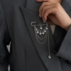 Detailed view of a silver safety pin brooch with tiered heart chains on a grey blazer