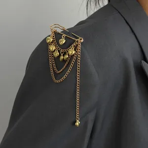 Close-up of gold brooch pin with multiple heart charms and layered chains on blazer