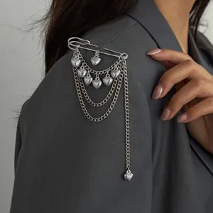 Close-up of a silver safety pin brooch with layered heart chains on a blazer
