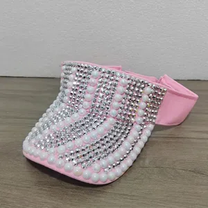 Detailaufnahme eines rosa Sonnenvisiers mit Reihen aus Strasssteinen und weißen Perlen.