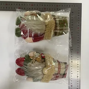 Pair of Nordic Christmas gnomes with plaid hats measured by a metal ruler.