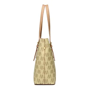 Side view detail of a beige printed tote bag with faux leather straps and gold hardware