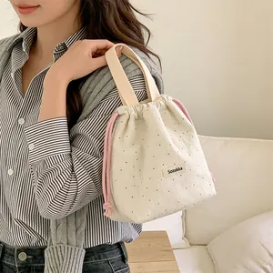 Detail of woolen polka dot drawstring handbag with pink ropes and woven handle