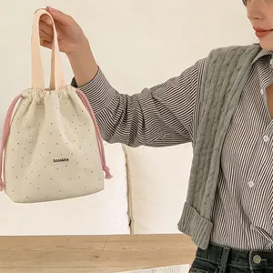 Detailed view of a stylish woolen polka dot drawstring bucket bag held by a model