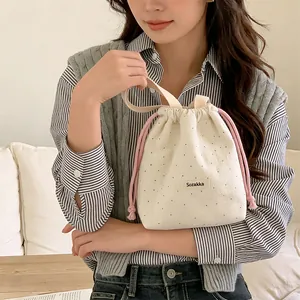 Close-up of a woolen polka dot drawstring bag with pink ropes and a top handle.