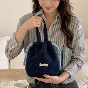 Stylish navy wool polka dot drawstring pouch bag held by a model in a casual setting