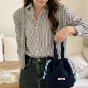 Detail view of navy wool drawstring pouch with white polka dots held by model