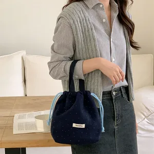 Close-up of navy blue wool drawstring bag with white polka dots held by model