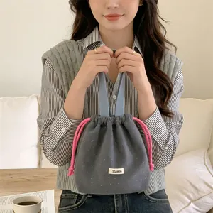 Detailed view of a grey wool drawstring handbag with white polka dots held by a model