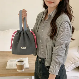 Detail of woolen polka dot drawstring bucket bag held by a person in a casual setting