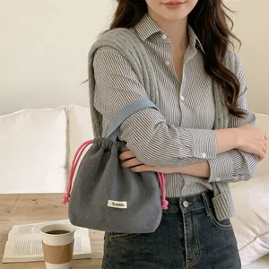 Detail of a grey woolen drawstring bucket bag featuring white polka dots pattern.