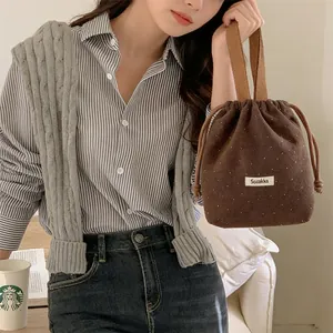 Brown polka dot wool drawstring bucket bag held by a model in a casual lifestyle setting