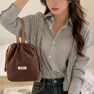 Detailed view of brown woolen drawstring bucket bag with small white polka dots