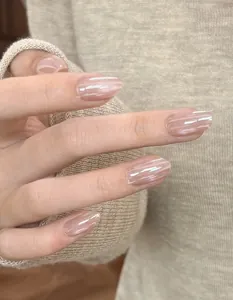 Detailed close-up showing glossy nude pink gradient oval press-on nails on a model's hand