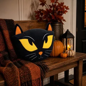 Cuscino di peluche a forma di gatto nero in un accogliente scenario di Halloween.