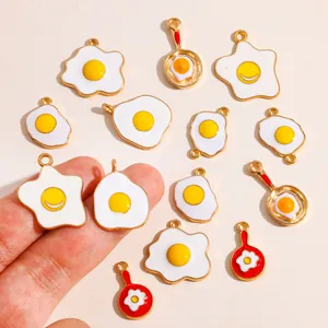 Close-up detail of various cartoon fried egg and frying pan enamel alloy charms for DIY