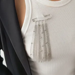 Detailansicht einer silbernen Sicherheitsnadel-Brosche mit eleganten hängenden Quastenketten.