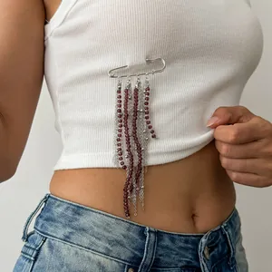 Detailansicht einer Brosche mit dunkelroten Perlen und silbernen Quastenketten auf Weiß