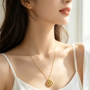 Elegant gold spiral pendant necklace worn by a female model in soft natural daylight