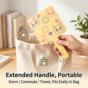 Portable yellow hand-held makeup mirror with cute cat patterns being placed in a bag
