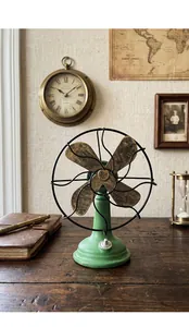 Vintage groene hars ventilator ornament met verweerde bladen op rustiek houten bureau
