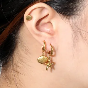 Close-up view of gold ocean-themed earrings featuring starfish and shell charms.
