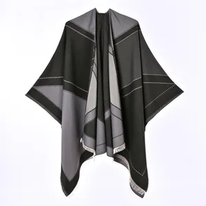 Detailed view of gray and black reversible poncho with geometric patterns and fringe
