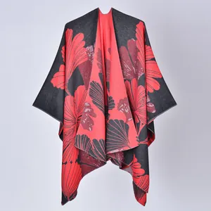 Close-up of a warm reversible shawl poncho with large red floral ginkgo leaf pattern.