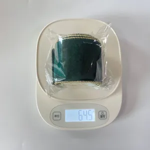 Green velvet ribbon roll with gold wire edge being weighed on a digital scale, 64.5g