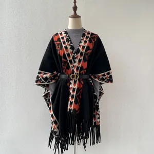 Détail d'un poncho en maille jacquard rétro avec des motifs orange et de longues franges
