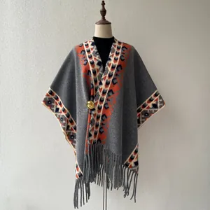 Gros plan sur le motif géométrique vintage et les détails de franges d'un poncho en tricot gris