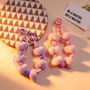 Nahaufnahme von lila und rosa Plüschball und Perlen-Herz Handy-Armbandanhänger im Detail