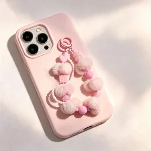 Nahaufnahme eines rosa Plüsch-Bommel und Herz-Perlen-Handybands